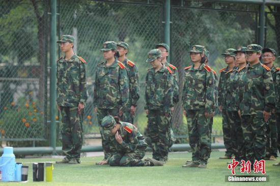 資料圖：一名女同學在軍訓隊伍中感到不適，跪在地上休息。 韋亮 攝